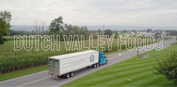 Dutch Valley Foods video still frame Still frame of a video showing a Dutch Valley Foods truck traveling down the highway with green fields in the background